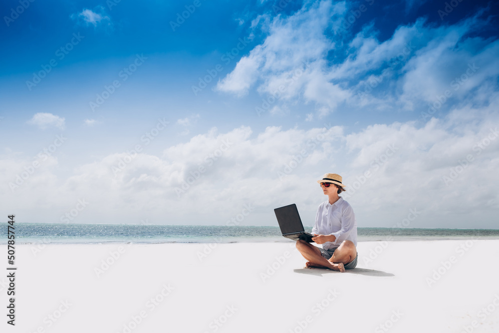 woman using and typing on laptop computer while sitting on the beach