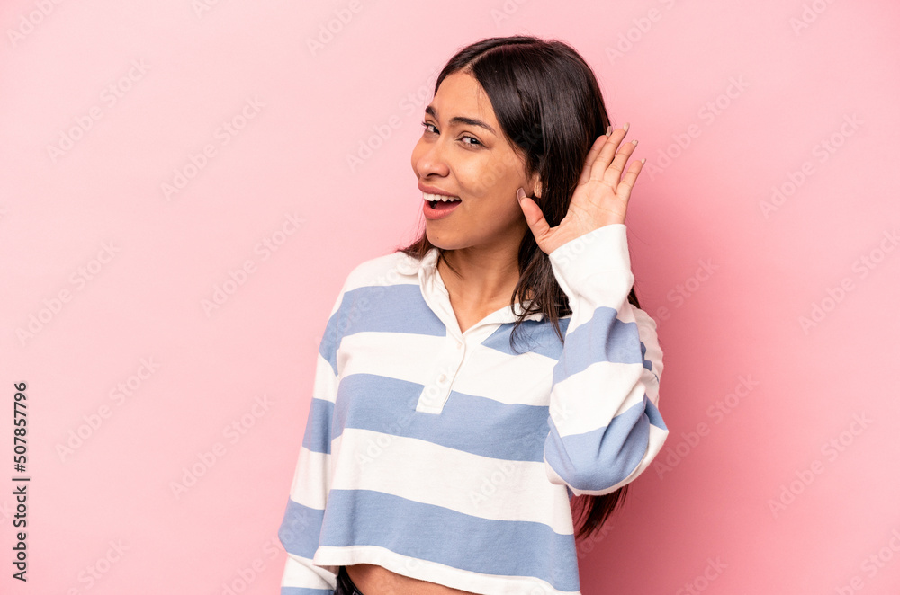 Young hispanic woman isolated on pink background trying to listening a gossip. Young hispanic woman isolated on pink background trying to listening a gossip.