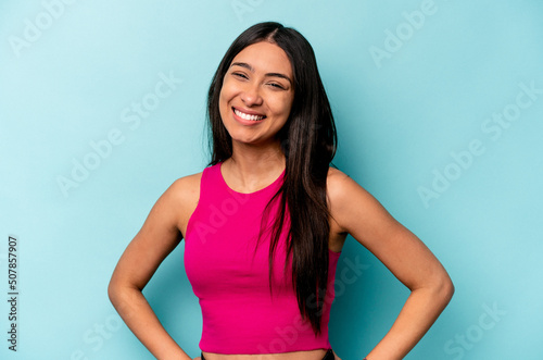 Photos Young hispanic woman isolated on blue background confident keeping hands on hips