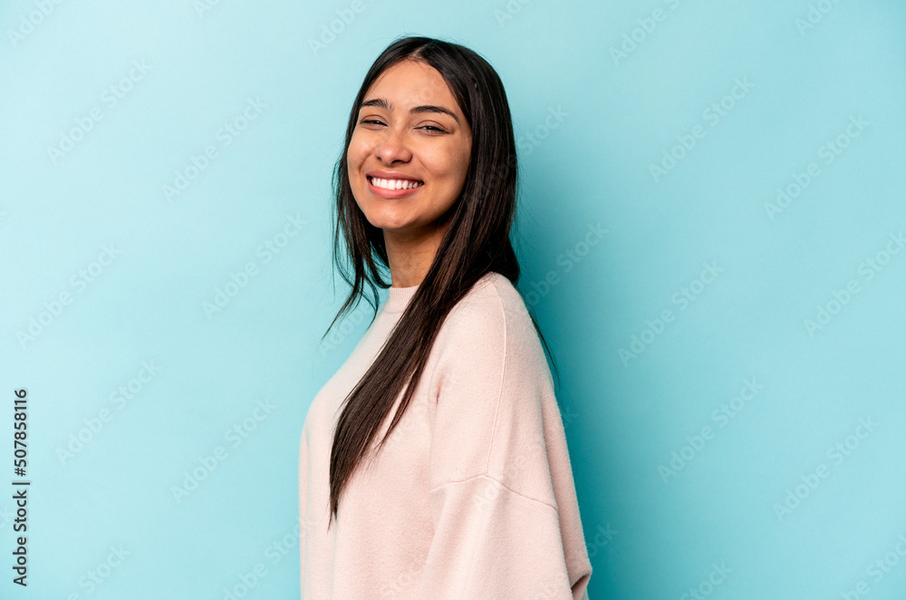 Young hispanic woman isolated on blue background confident keeping hands on hips.