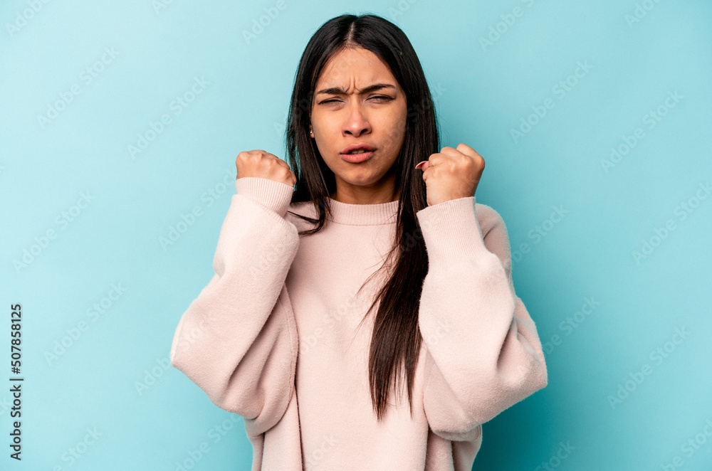Fototapeta premium Young hispanic woman isolated on blue background showing fist to camera, aggressive facial expression.