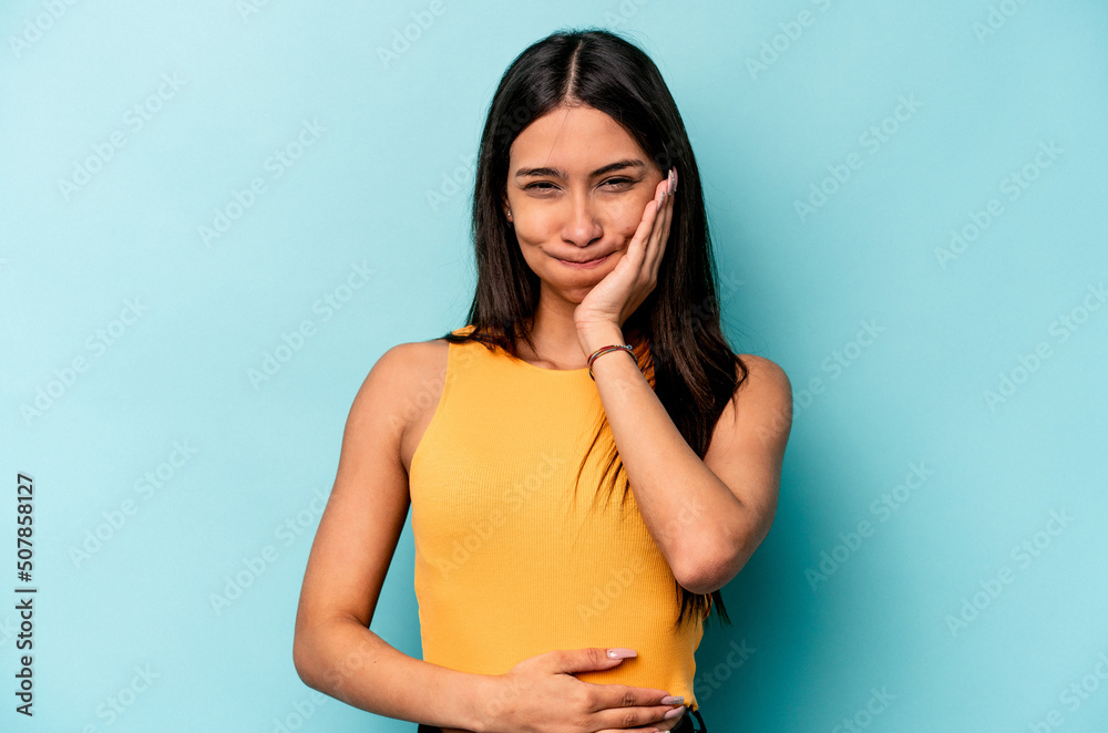 Young hispanic woman isolated on blue background blows cheeks, has tired expression. Facial expression concept. Young hispanic woman isolated on blue background blows cheeks, has tired expression. Facial expression concept.