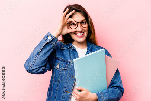 Young student caucasian woman isolated on pink background excited keeping ok gesture on eye.