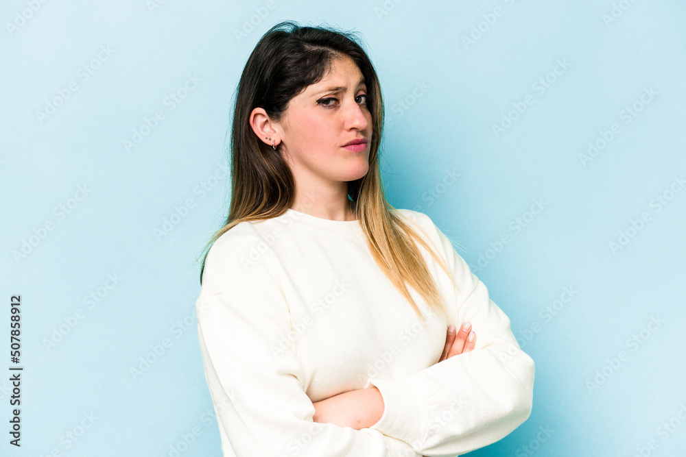 Young caucasian woman isolated on blue background suspicious, uncertain, examining you.