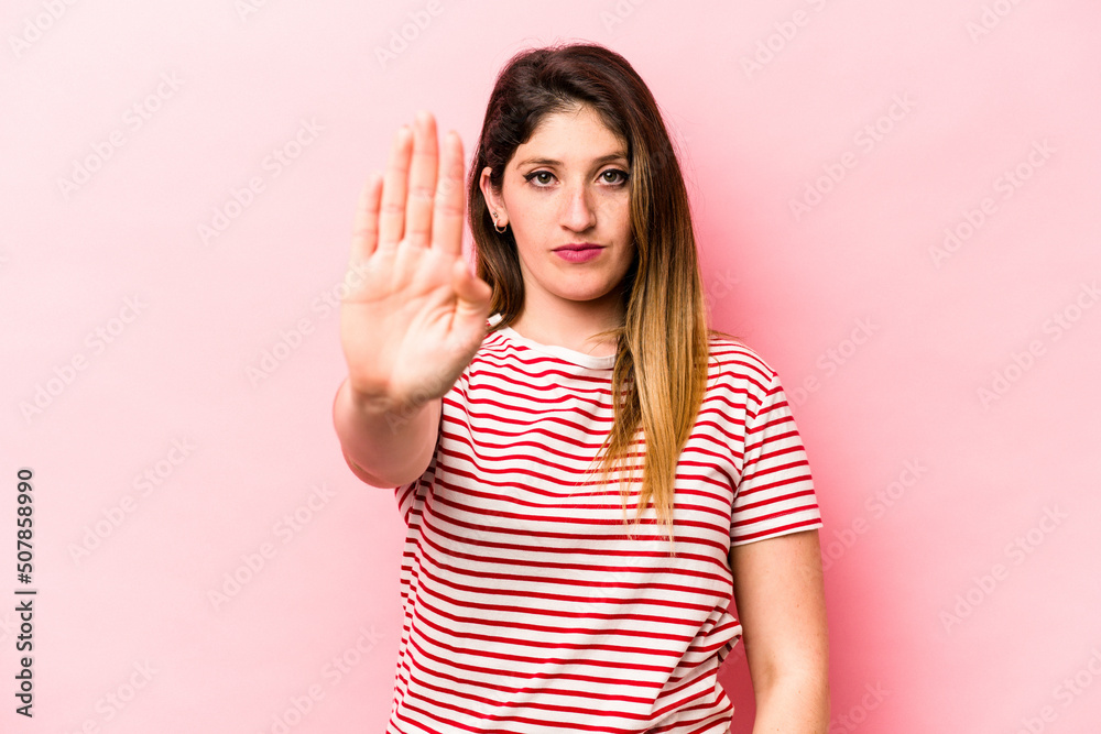 Young caucasian woman isolated on pink background standing with outstretched hand showing stop sign, preventing you. Young caucasian woman isolated on pink background standing with outstretched hand showing stop sign, preventing you.