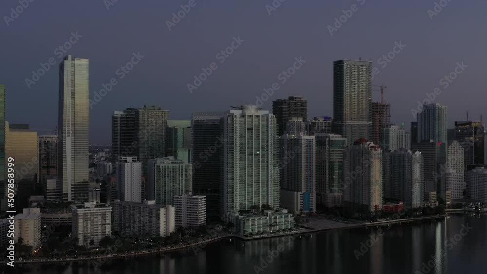 Night time aerial view across Miami waterfront futuristic tall skyscrapers along coastline Night time aerial view across Miami waterfront futuristic tall skyscrapers along coastline