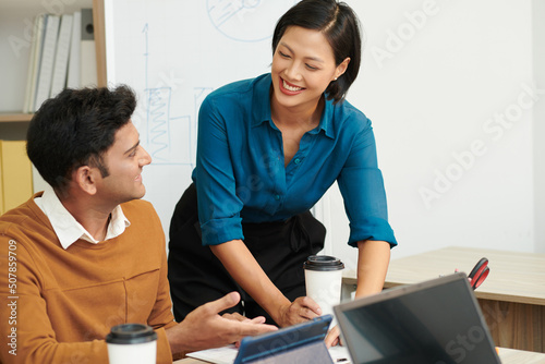 Smiling businesswoman helping new coworker to get used to work in new environmant photo