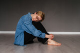 Young woman with closed eyes and short hair sitting on the floor meditating indoors. Girl doing yoga exercise in studio