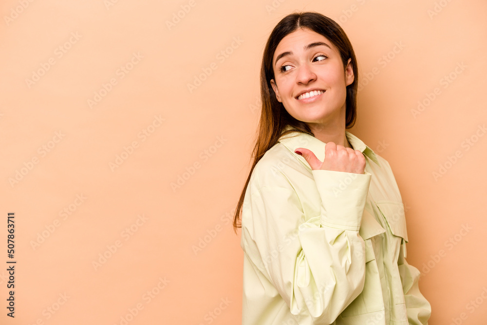 Young hispanic woman isolated on beige background points with thumb finger away, laughing and carefree. Young hispanic woman isolated on beige background points with thumb finger away, laughing and carefree.