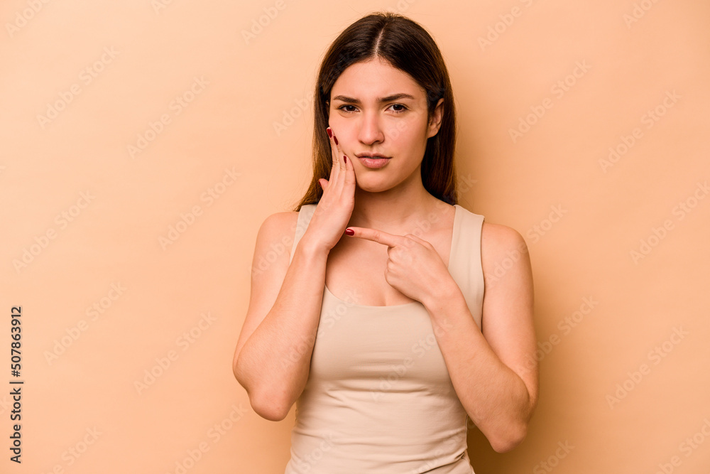 Young hispanic woman isolated on beige background having a strong teeth pain, molar ache.