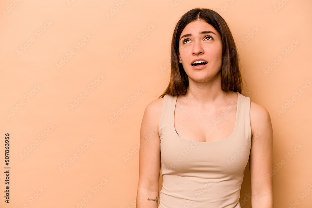 Obraz premium Young hispanic woman isolated on beige background shouting very angry, rage concept, frustrated.