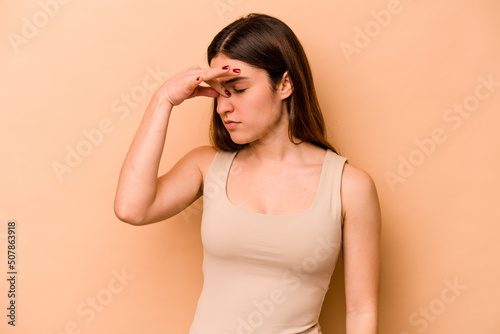 Young hispanic woman isolated on beige background having a head ache, touching front of the face.