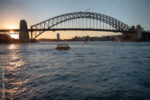 Large bridge across the bay at sunset with a small boat on the water, Harbour Bridge, Sydney, Australia
