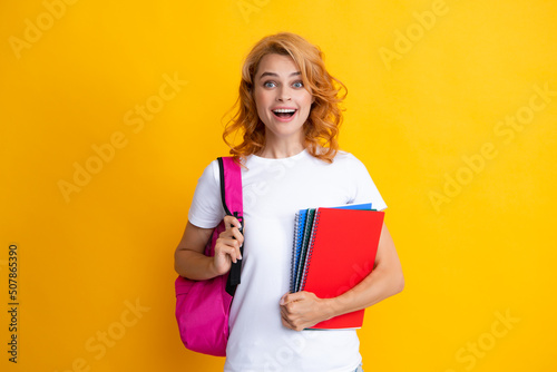 Cute student woman with backpack holds some documents and books over yellow background.