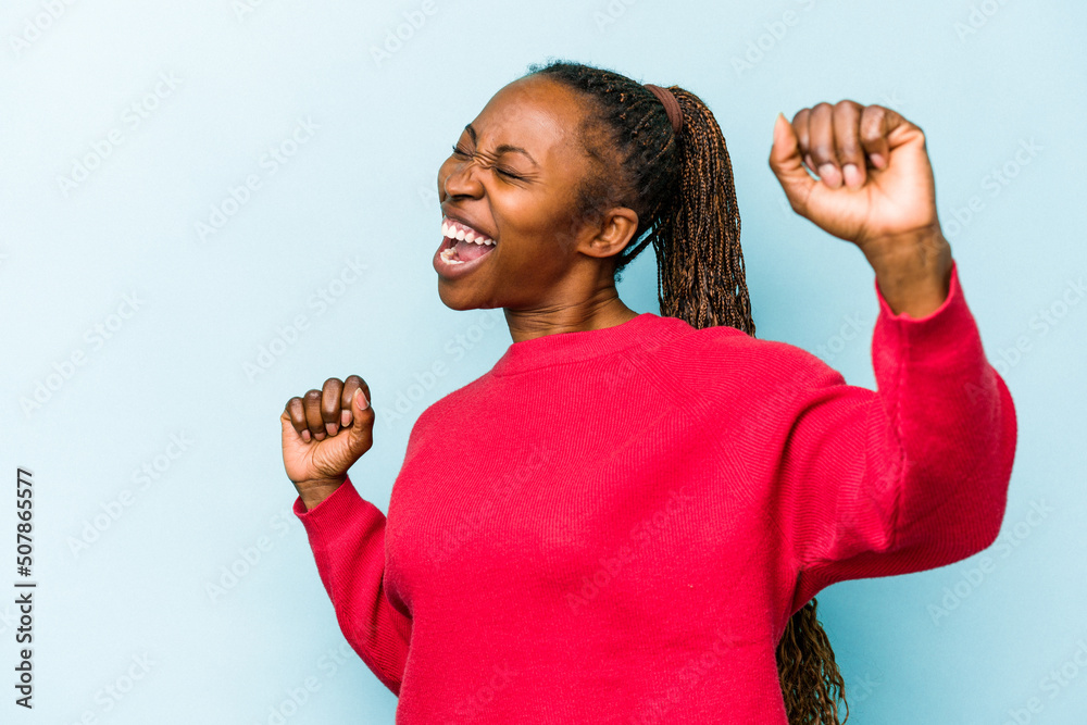 Young african american woman isolated on blue background dancing and having fun. Young african american woman isolated on blue background dancing and having fun.
