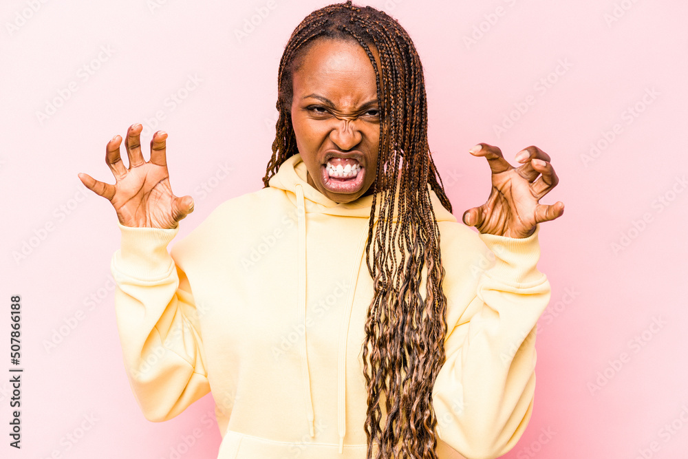 Young african american woman isolated on pink background upset screaming with tense hands. Young african american woman isolated on pink background upset screaming with tense hands.