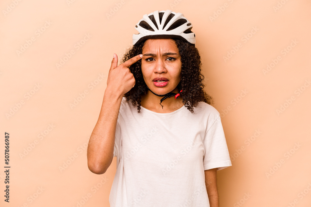 Young hispanic woman wearing a helmet bike isolated on blue background showing a disappointment gesture with forefinger. Young hispanic woman wearing a helmet bike isolated on blue background showing a disappointment gesture with forefinger.