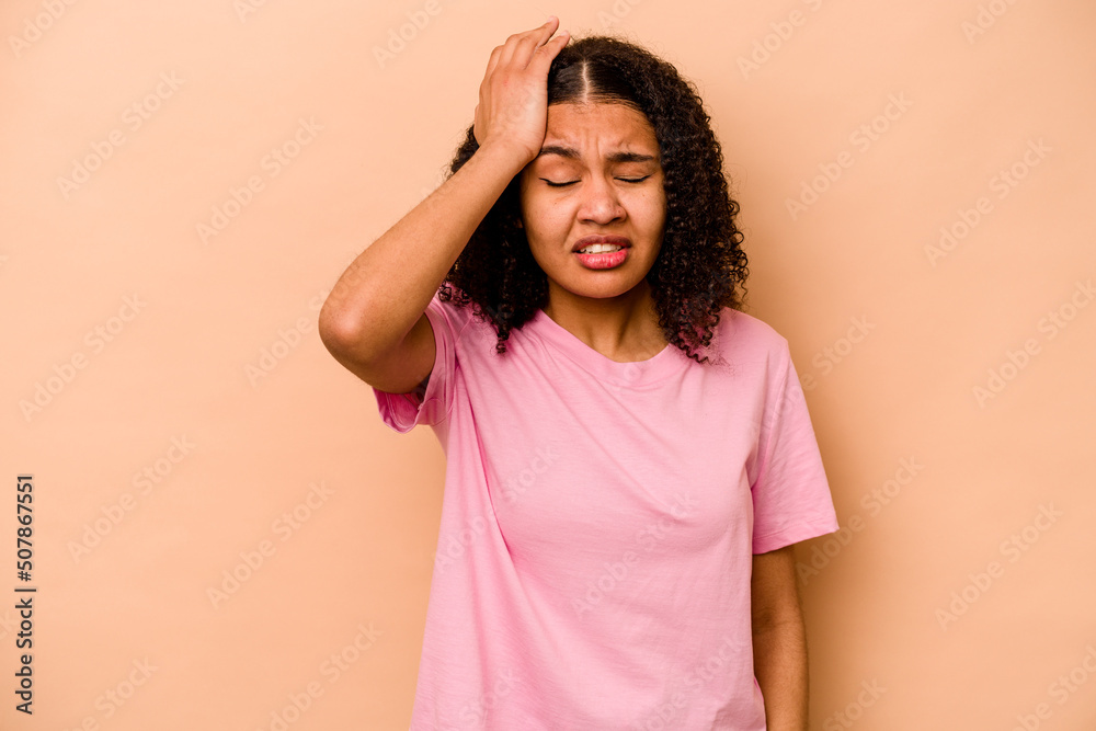 Young African American woman isolated on beige background forgetting something, slapping forehead with palm and closing eyes. Young African American woman isolated on beige background forgetting something, slapping forehead with palm and closing eyes.