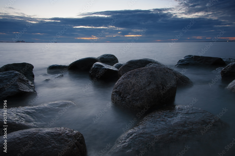 Obraz premium Big stones stones on the shore in water at night. Long exposure nature seascape photography