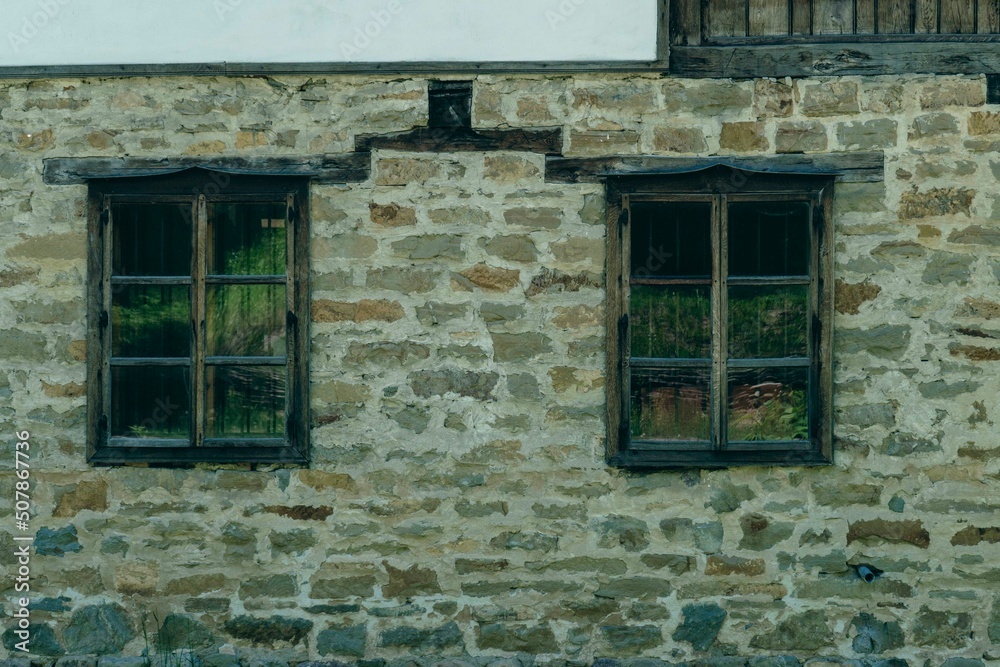 old stone wall with two old wooden windows old stone wall with two old wooden windows