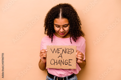 Photographie Young African american woman holding we need a change placard isolated on beige