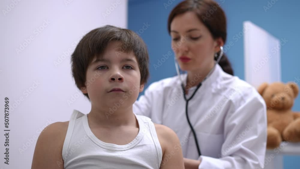 Portrait of Caucasian boy inhaling and exhaling as doctor listening auscultation with stethoscope. Male patient undergoing routine medical examination in hospital indoors Portrait of Caucasian boy inhaling and exhaling as doctor listening auscultation with stethoscope. Male patient undergoing routine medical examination in hospital indoors
