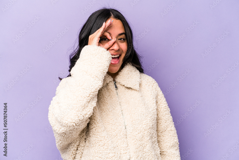 Young hispanic woman isolated on purple background excited keeping ok gesture on eye. Young hispanic woman isolated on purple background excited keeping ok gesture on eye.