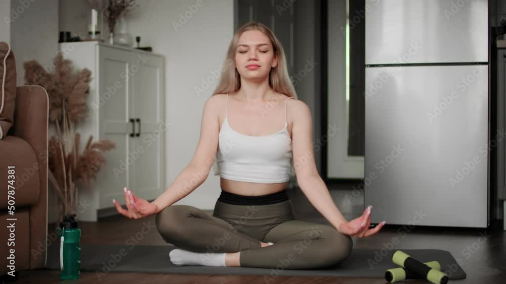 The girl is doing yoga sitting on the floor in the lotus position at ...