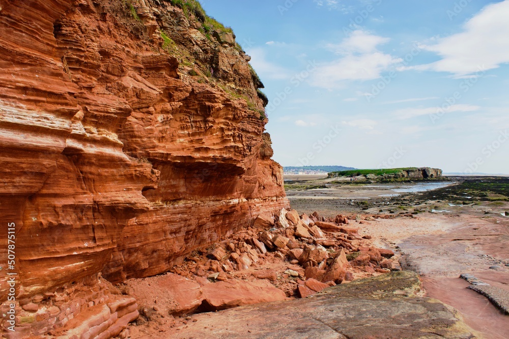 Red cliffside on beach island.