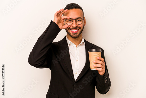 Young business hispanic man holding takeaway coffee isolated on white background excited keeping ok gesture on eye.