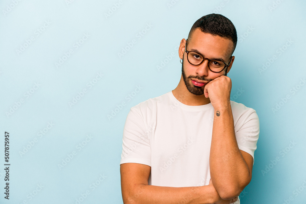 Young hispanic man isolated on blue background who feels sad and pensive, looking at copy space. Young hispanic man isolated on blue background who feels sad and pensive, looking at copy space.