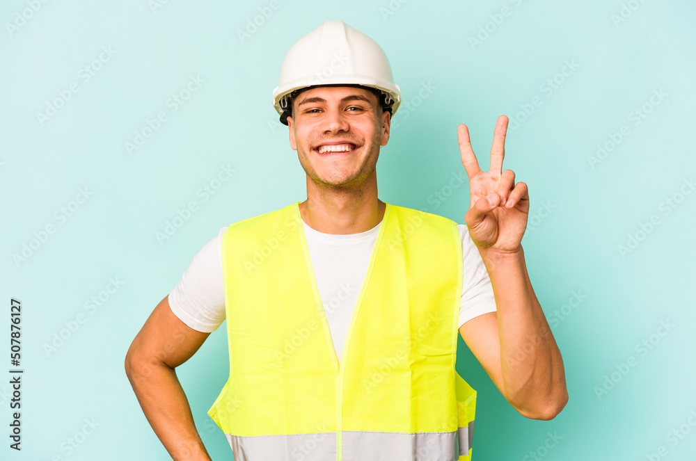Young laborer caucasian man isolated on blue background showing number two with fingers.