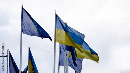 Ukrainian national flag and the flag of the European Union is unfolding in the wind with the sky background