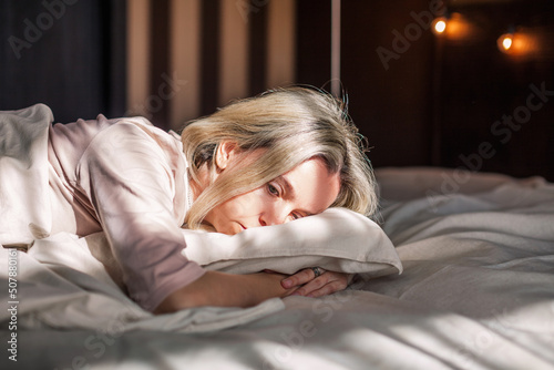 Unhappy sad middle aged woman sitting on bed at home photo