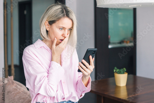 Foto middle-aged woman holding phone, reading unpleasant news in social media