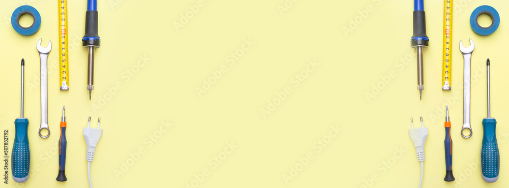 Banner with repair tools on a yellow background. Measuring tape, screwdriver, wrench. Place for text. Copy space. Flat lay. Top view. Handyman tool kit. Banner with repair tools on a yellow background. Measuring tape, screwdriver, wrench. Place for text. Copy space. Flat lay. Top view. Handyman tool kit.
