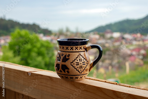 Coffee mug with Romanian ethnic motifs, and a defocused high view over Gura Humorului city photo