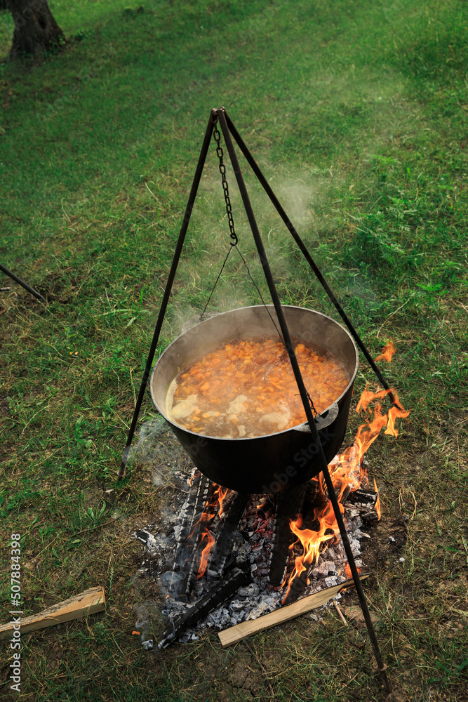 Cauldron suspended over the fire, cooking in the field. Food is cooked in the open air on the fire Cauldron suspended over the fire, cooking in the field. Food is cooked in the open air on the fire
