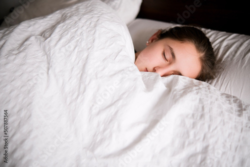 Tableau sur toile Chica dormida en una cama de colcha blanca.