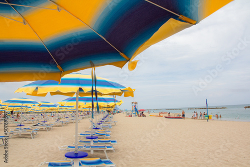 Beach umbrellas and couches on blue sky and sea background on the beach of Italy. Popular Tourist Resort at Adriatic Sea on beach of , Rimini Adriatic coast, Italy photo