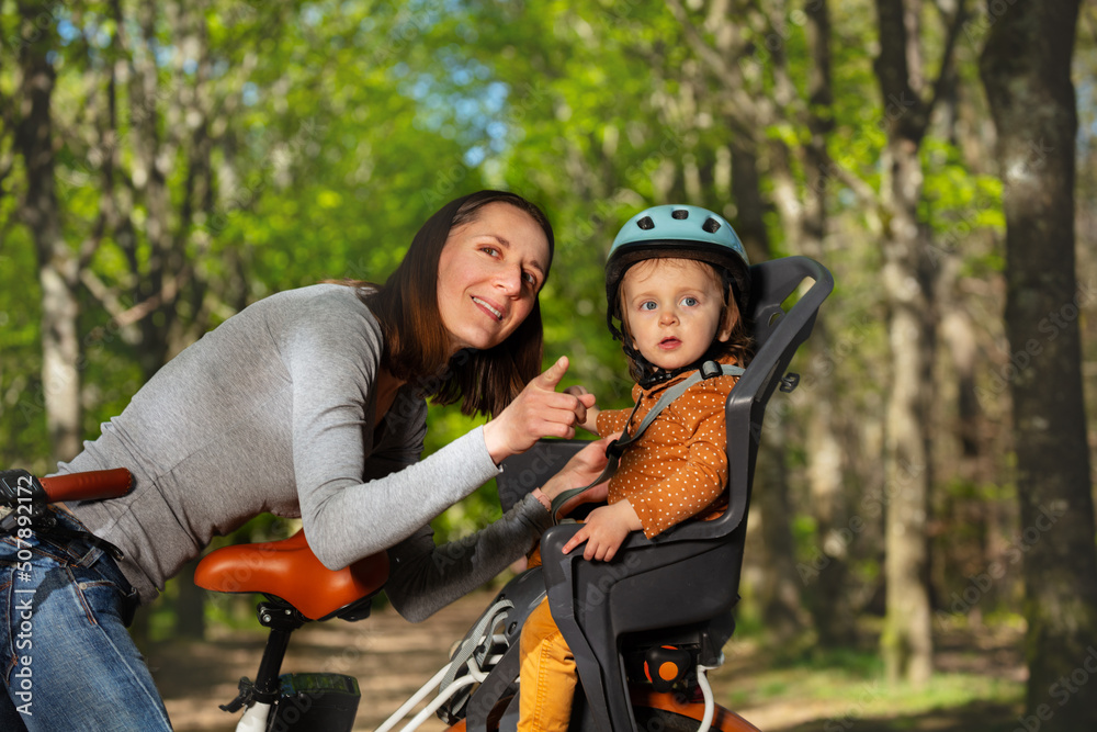 Woman play with child sitting in electric bike pointing finger