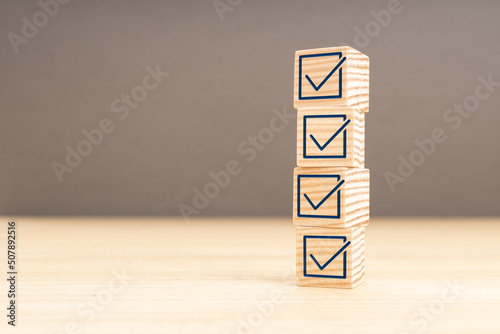 Checking or checklist concept. Wooden block with check icon stacked on wooden table. Copy space