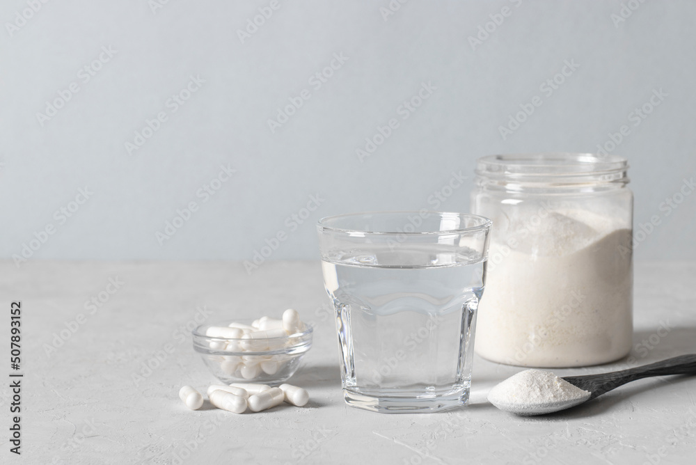 Collagen powder in spoon, glass of water, collagen capsules and jar of powder on light blue background. Healthy anti-aging concept Collagen powder in spoon, glass of water, collagen capsules and jar of powder on light blue background. Healthy anti-aging concept