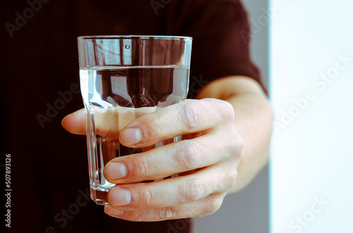 A man's hand with a glass of pure spring water