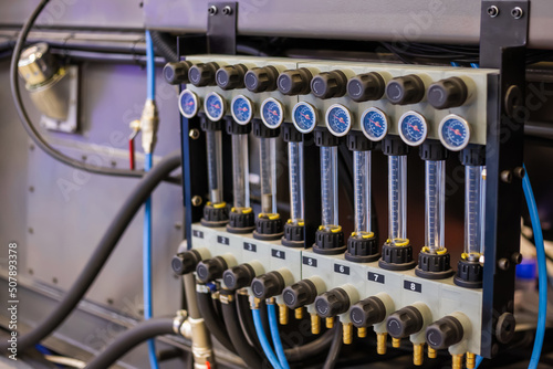 Flowmeter, rotameter - water flow regulator for cooling system of injection moulding machine at plant, factory - close up. Measuring and control equipment concept photo