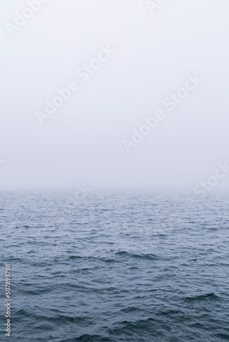 Fototapeta Naklejka Na Ścianę i Meble -  View of waves on the ocean with vanishing horizon on a foggy day. Copy space. Good for natural sea background.
