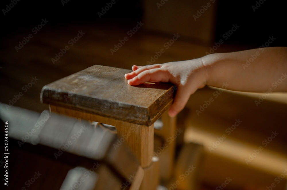 the kid is playing at home in a room with bright sunlight with a large wooden car