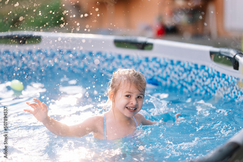 Sweet 3 years old girl enjoys summer time in swimming pool at the backyard of her home  stay home vacation concept