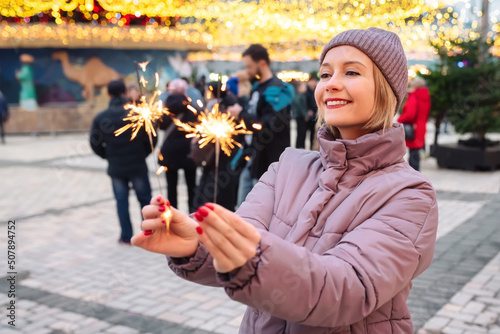 Happy girl with sparklers in her hands outdoors on Christmas days. New Year party, Winter holiday