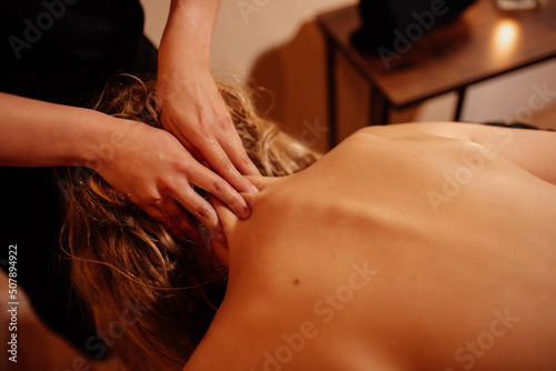 hands of unrecognizable person massaging the neck of a white woman lying down on the stretcher of a beauty and wellness center